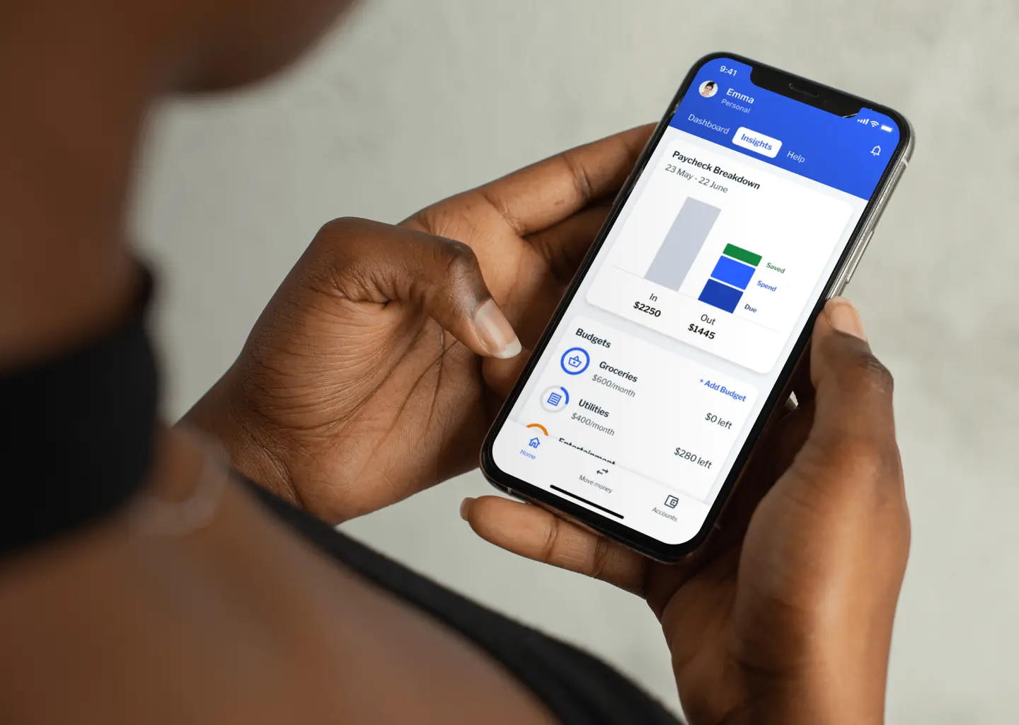 Hands holding a phone showing the Backbase banking app&rsquo;s paycheck breakdown and budgets.